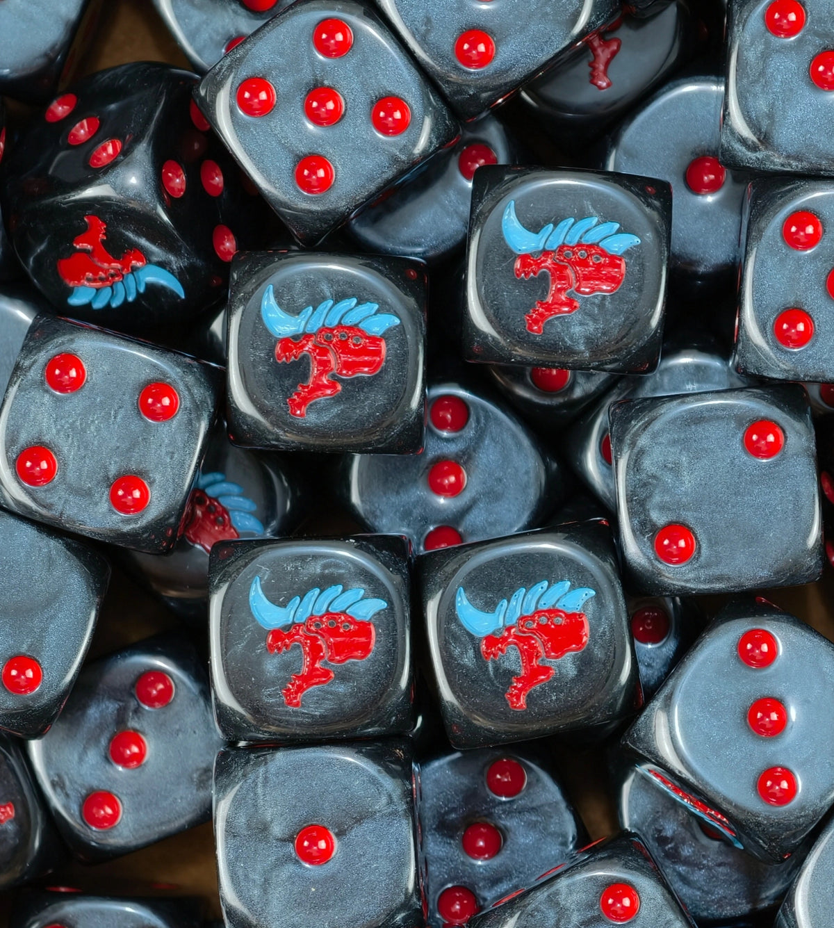 A pile of black Tyranid dice, red alien heads with blue crests and red pips repeating