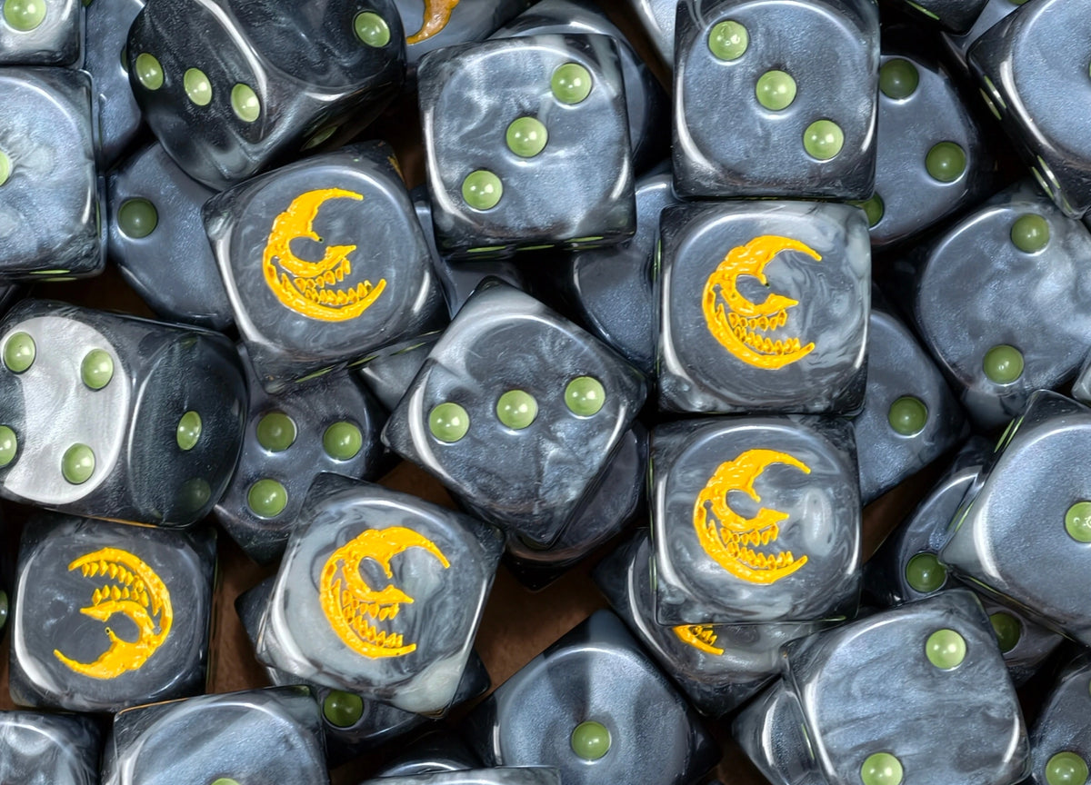 A pile of black goblin dice, yellow grinning moons and olive green pips repeating