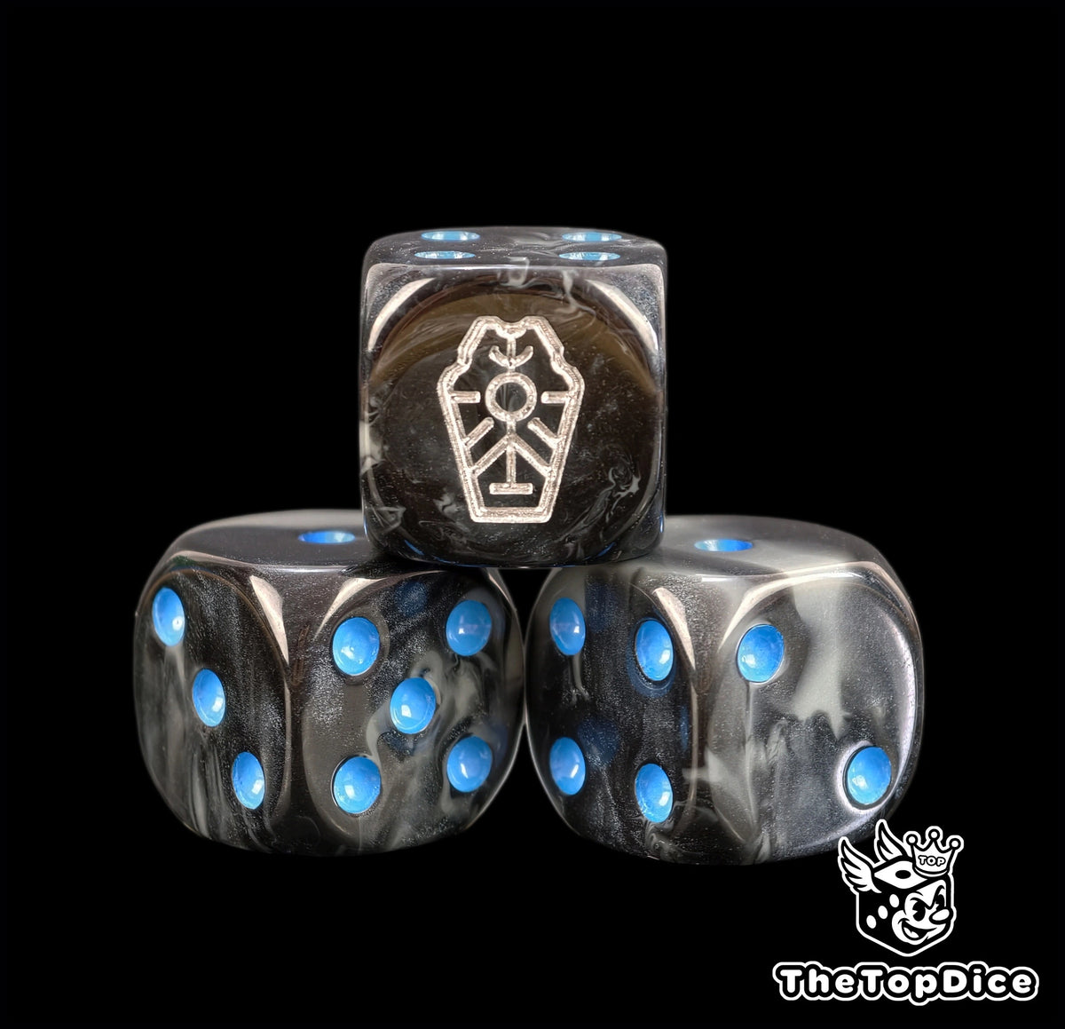 Close up of three blue Necron dice, black grey marbled resin with a silver dynasty glyph and blue pips