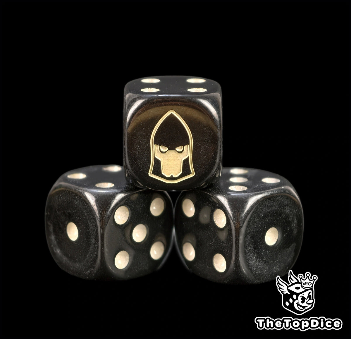 Three black Eldar seer dice with bone pips and a gold helm emblem