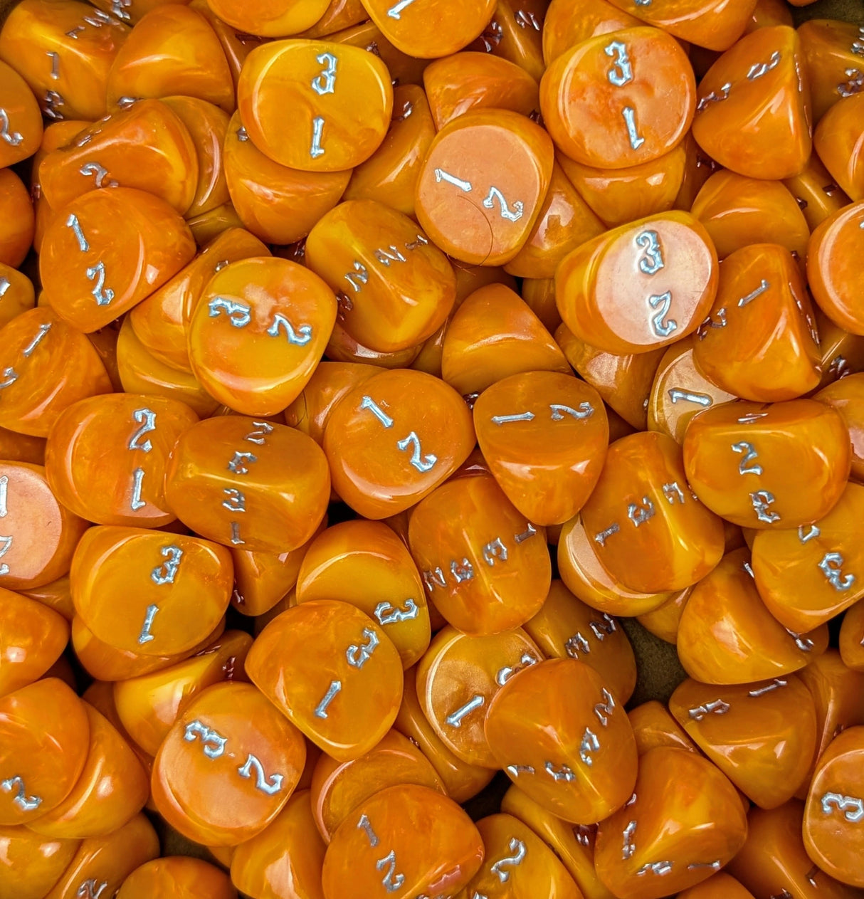 Pile of orange D3 three sided dice for tabletop games