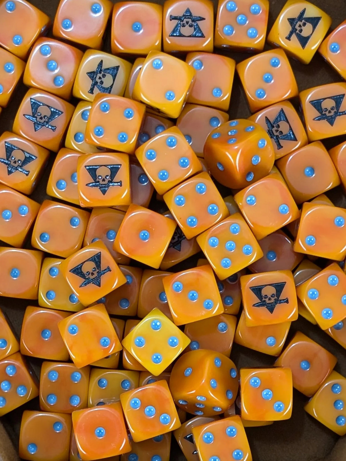 Pile of orange 16mm D6 dice with black skull emblems for a sci-fi skirmish squad
