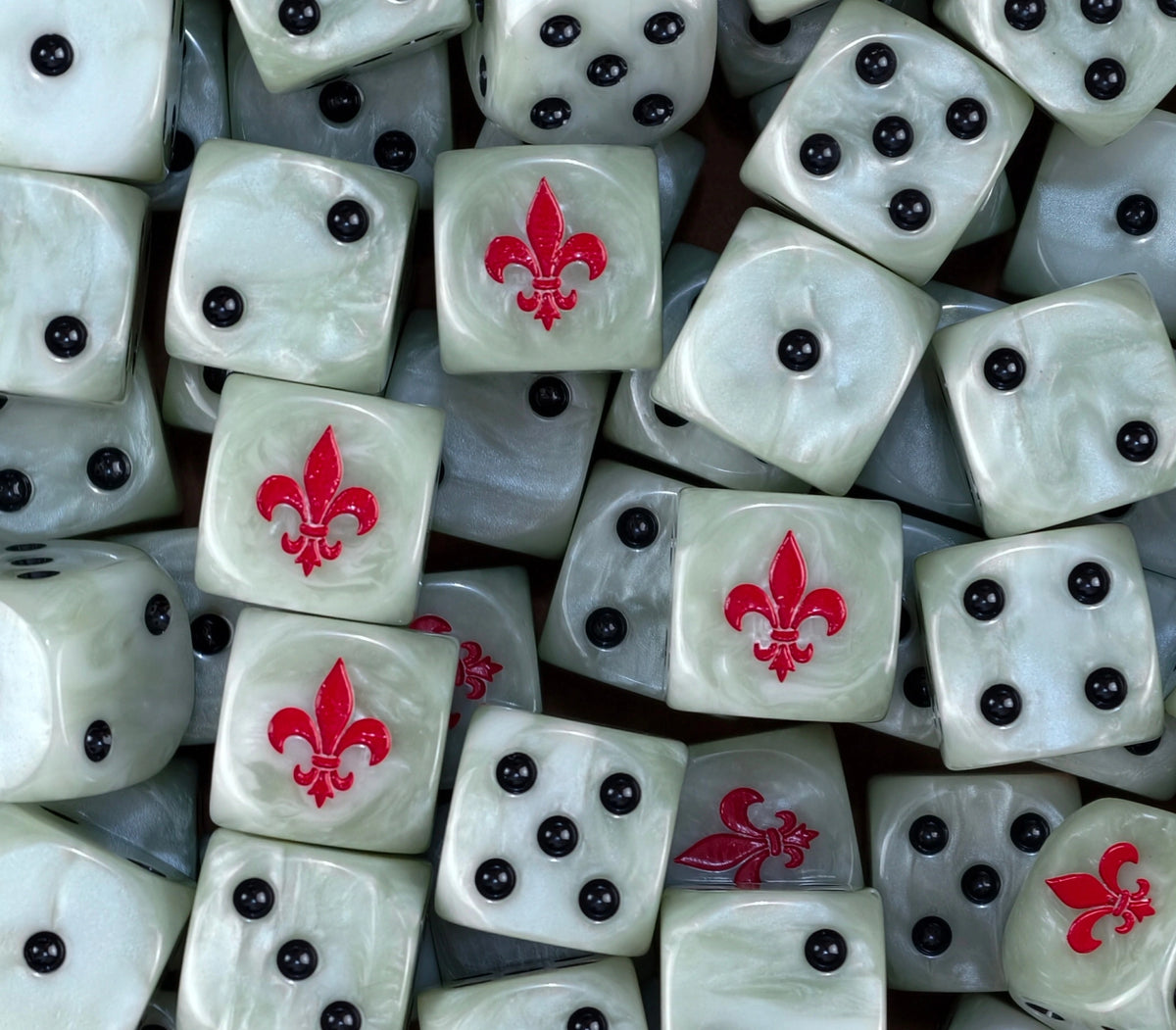A pile of bone white Battle Sisters dice with red fleur de lis emblems