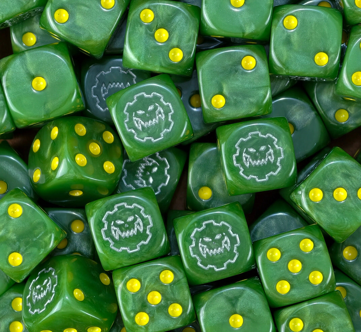 A pile of green orc D6 with yellow pips and silver Ork cog skulls