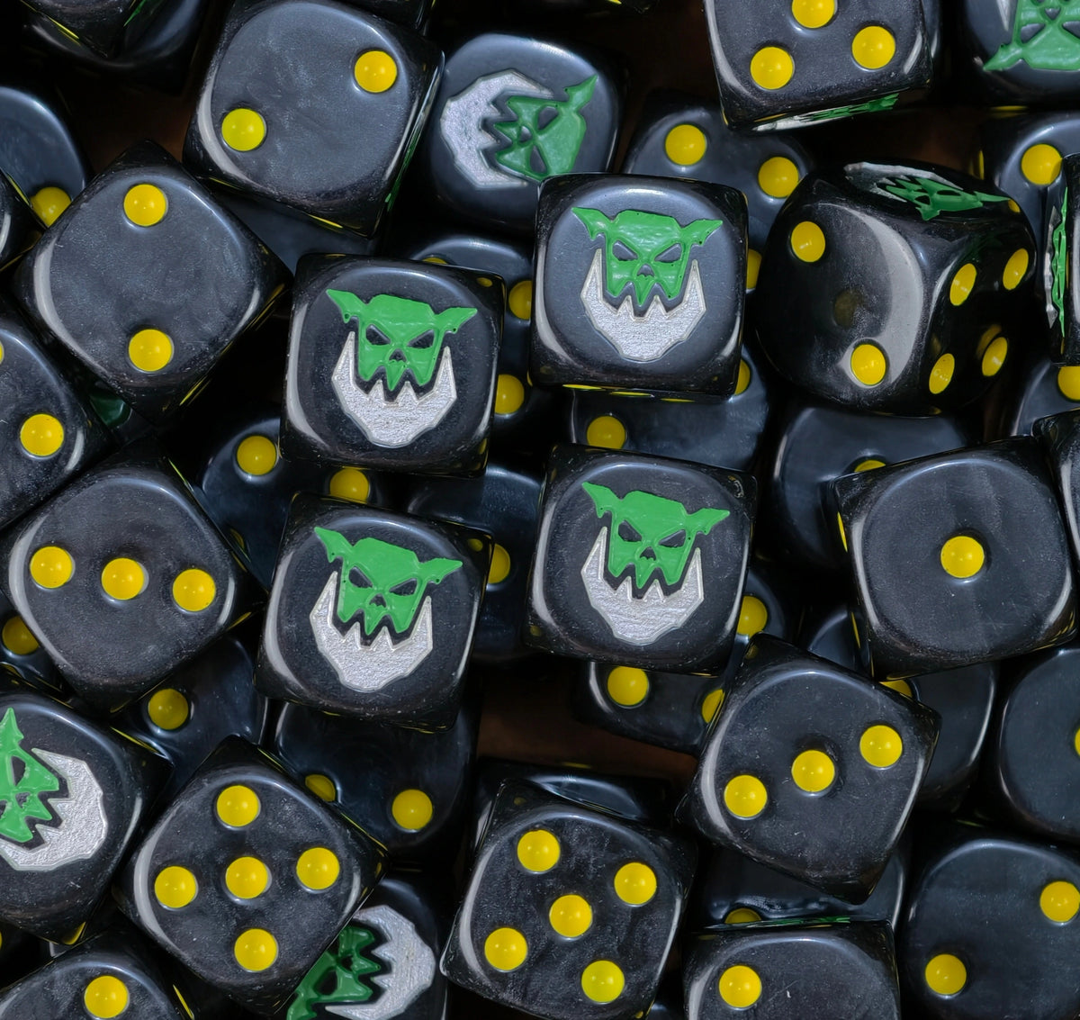 dados inspirados en los orkos iron jawz de warhammer de age of sigmar de base de color negro puntos amarillos y el logo es una cara de orko verde que tiene una mandibula de iron color silver