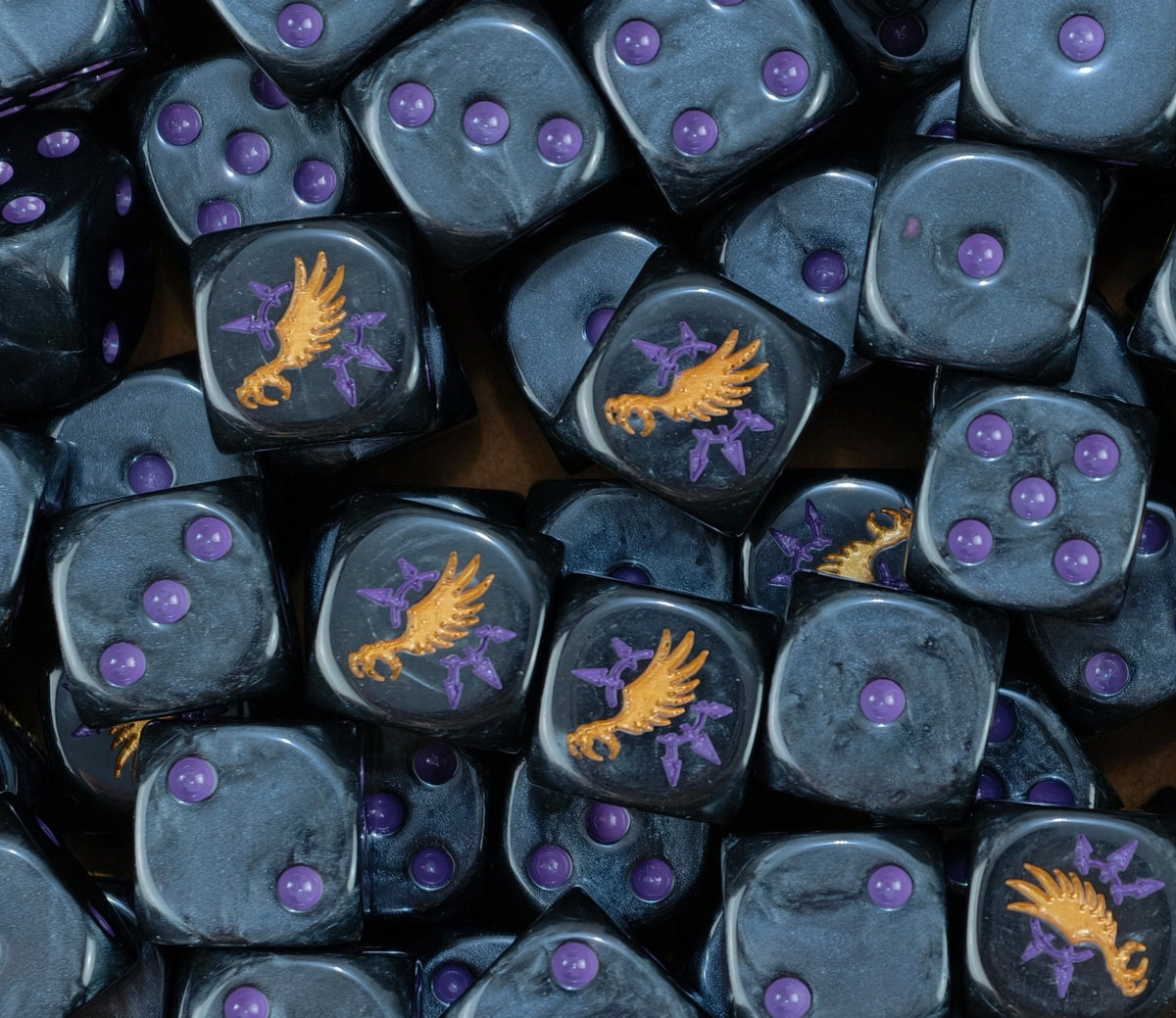 dados inspirados en los emperor of children de warhammer de base de color negro puntos purple y el logo es una garra con alas doradas y le rodea puntas del chaos purple