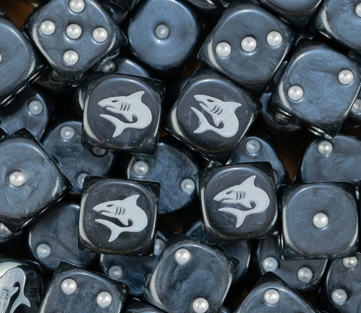 A pile of black Carcharodons dice, white sharks and silver pips repeating