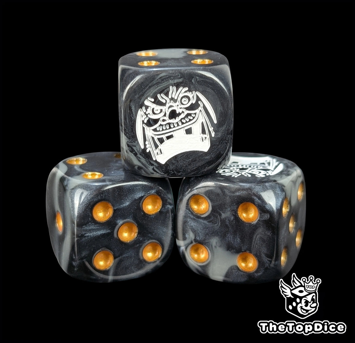 Close up of a black and grey 16mm resin D6 die engraved with a white laughing emblem and gold pips