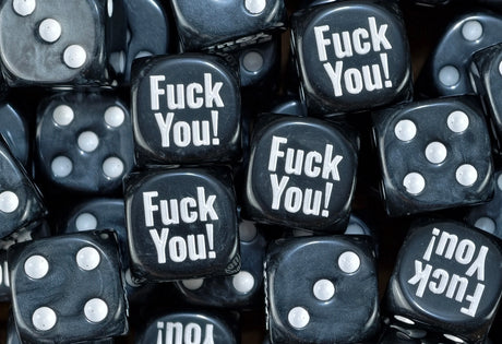 A pile of black Fuck You meme D6 with bone white pips and print