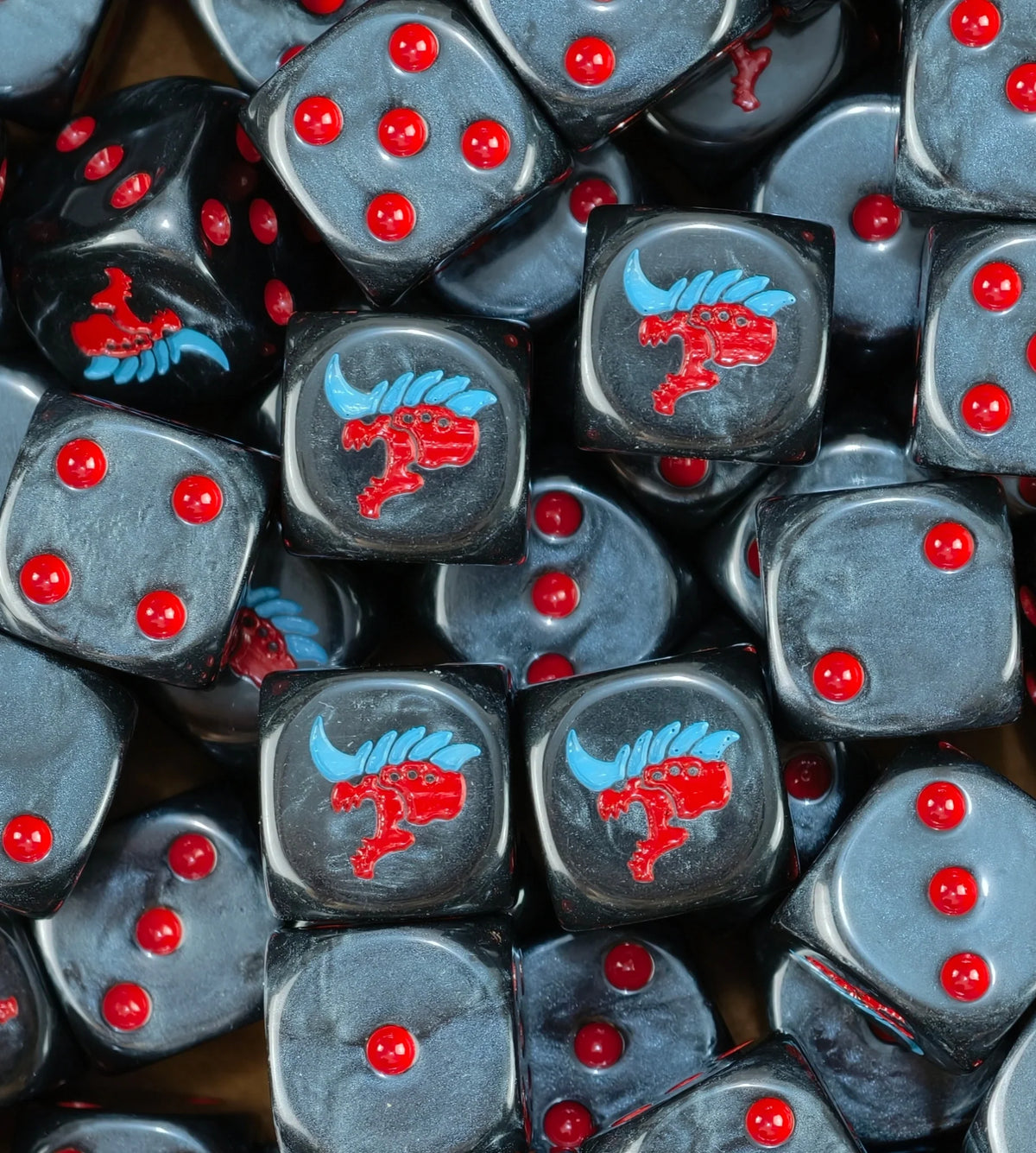 A pile of black Tyranid dice, red alien heads with blue crests and red pips repeating