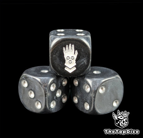 Close up of a black 16mm resin D6 die engraved with a white iron hand and silver pips