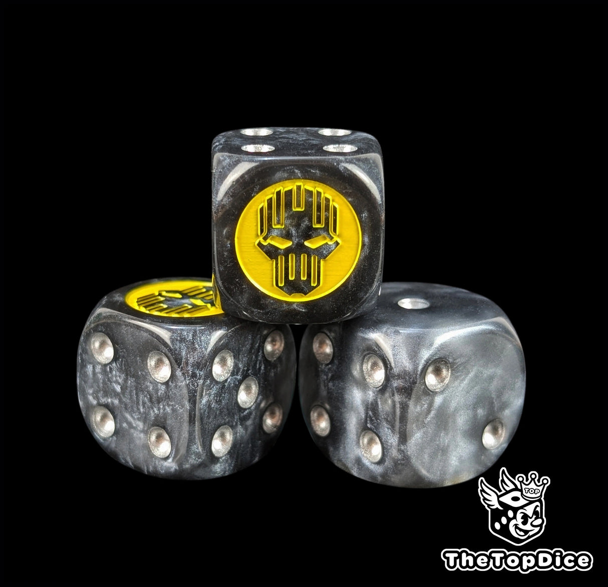 Close up of a black and grey 16mm resin D6 die engraved with a yellow helm silhouette and silver pips