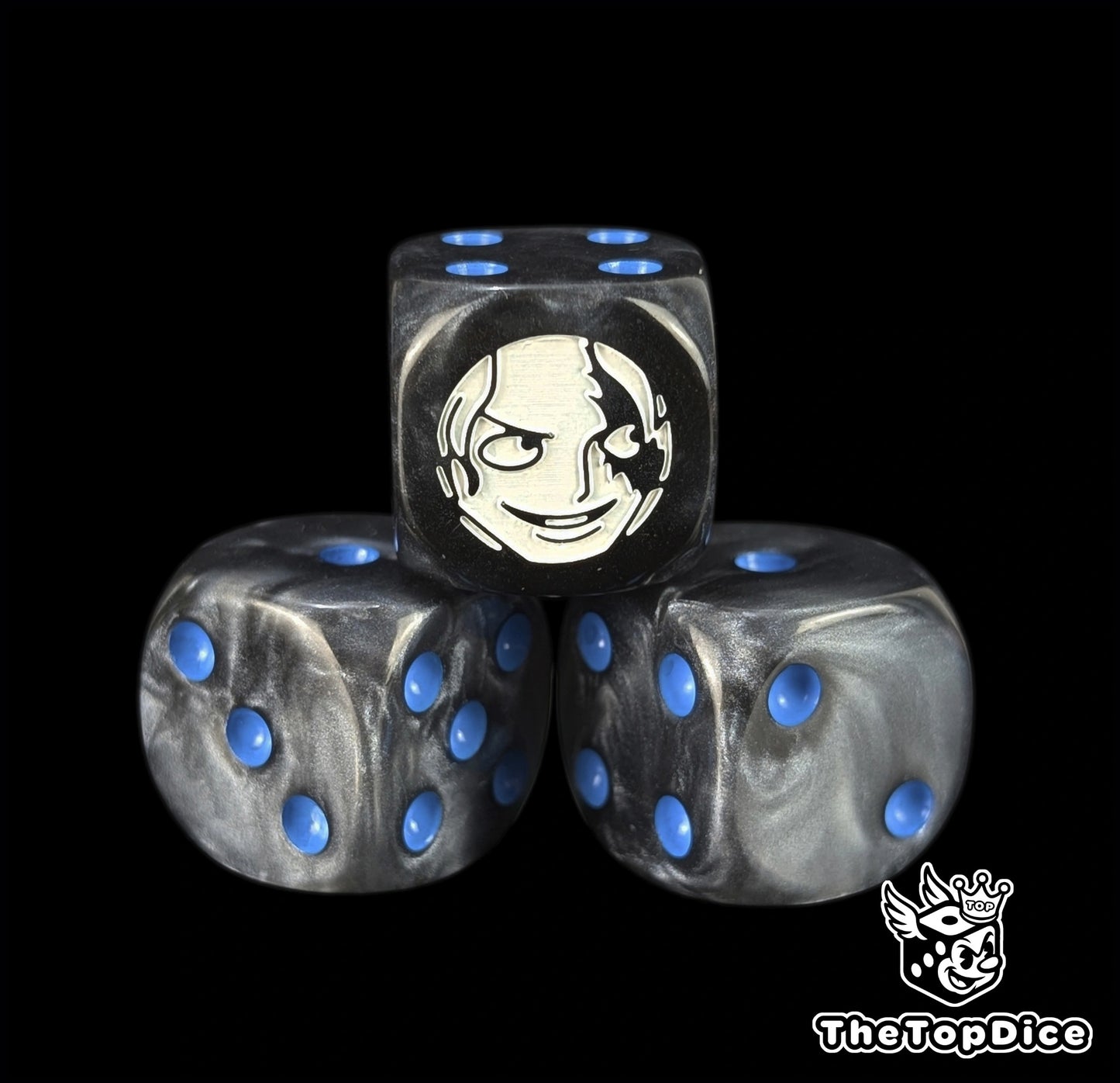Close up of a black 16mm resin D6 die engraved with a white fighter emblem and blue pips