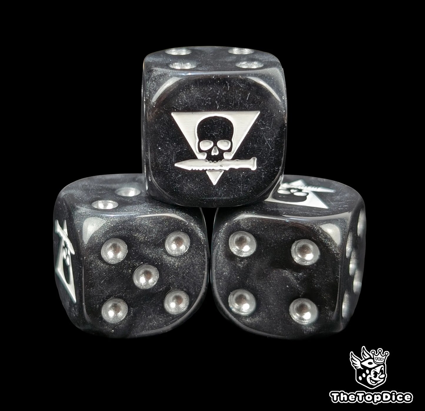 Close up of a black 16mm resin D6 die engraved with a triangle skull biting a white knife