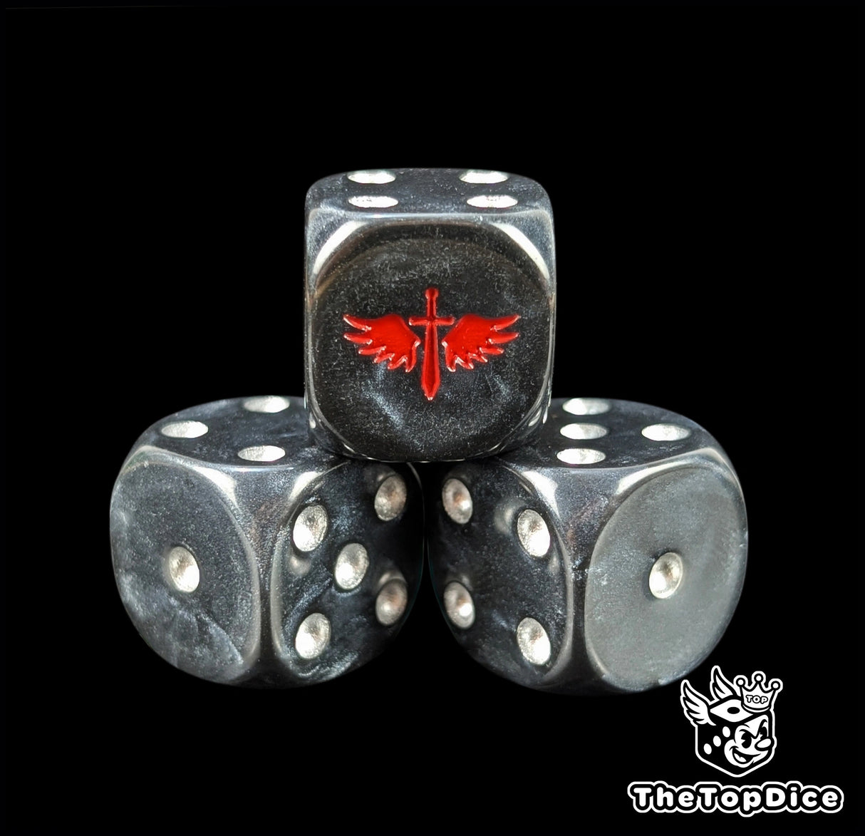 Close up of a black 16mm resin D6 die engraved with a red winged sword and silver pips