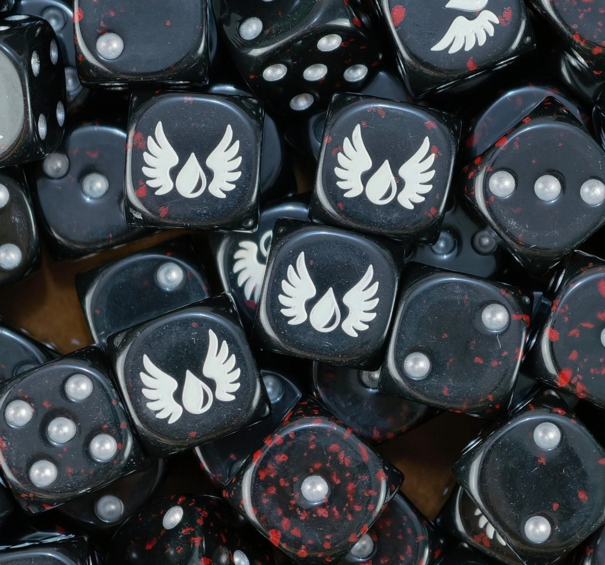 Pile of black blood splatter dice with white winged blood drops and silver pips for a Blood Angels army