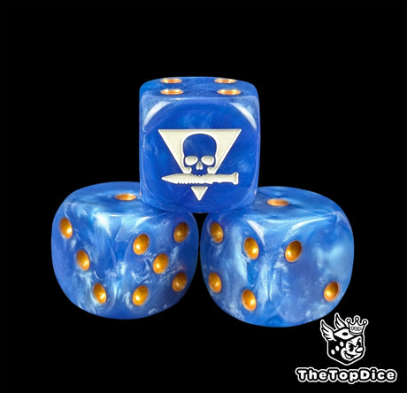 Close up of a blue 16mm resin D6 die engraved with a white squad sigil and gold pips
