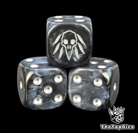 Close up of a black 16mm resin D6 die engraved with a grey raven skull and silver pips