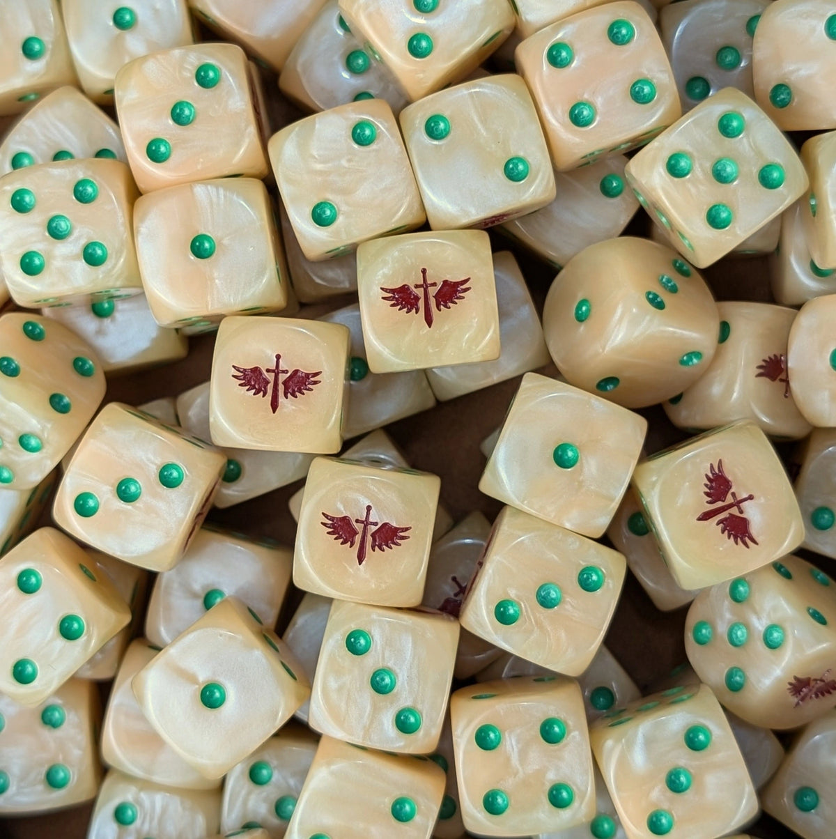 Pile of bone white Dark Angels Deathwing dice with green pips and red winged swords