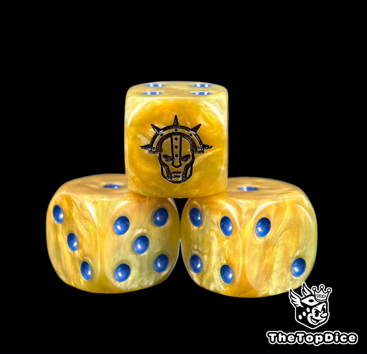 Three gold Stormcast dice with blue pips and a black war helm