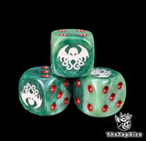 Close up of a green 16mm resin D6 die engraved with a white Cthulhu cult sigil and red pips