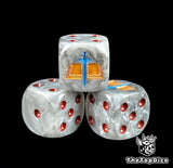 Close up of a grey 16mm resin D6 die engraved with a gold tome and blue blade and red pips