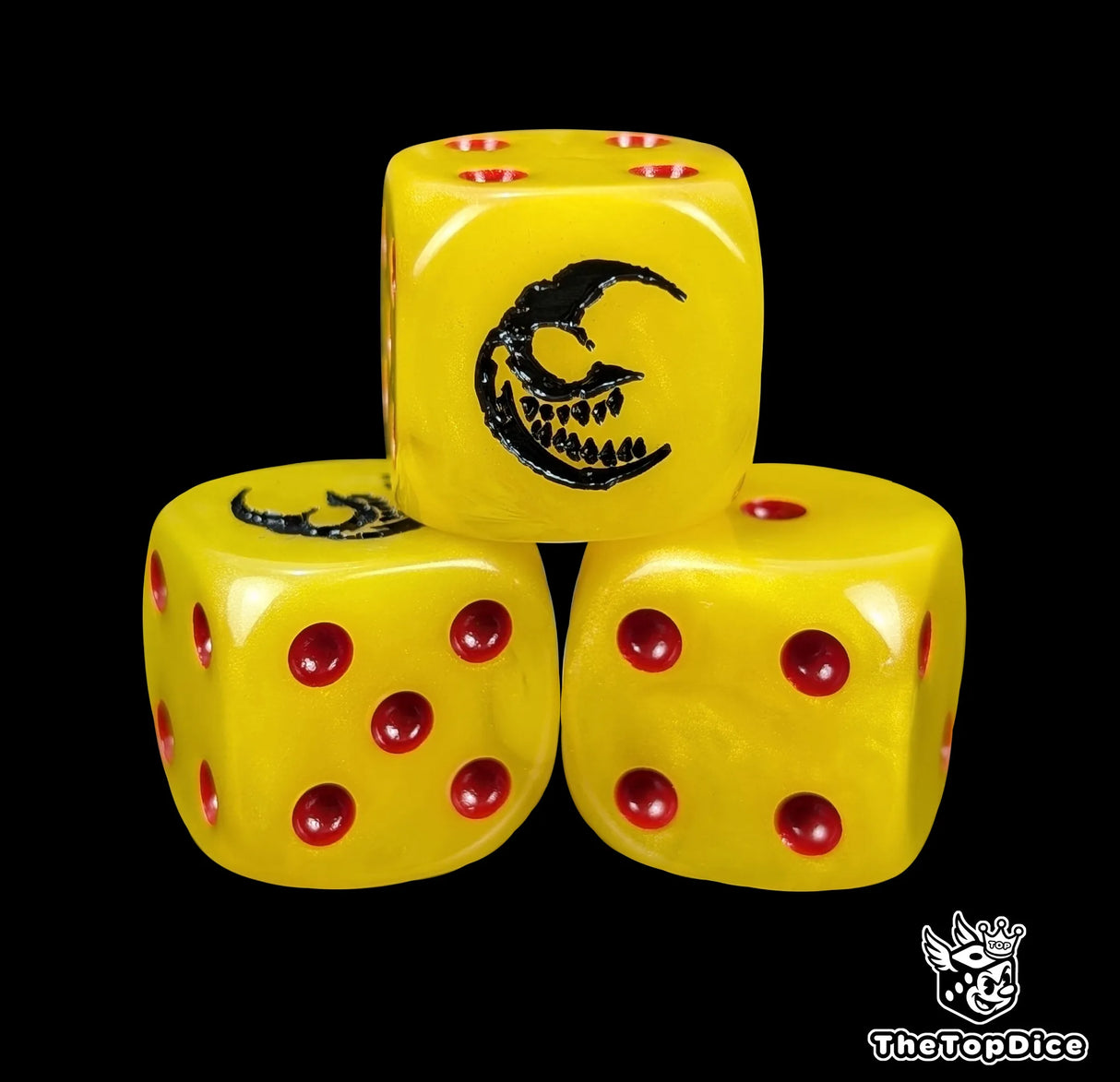Close up of a yellow 16mm resin D6 die engraved with a black grinning crescent moon and red pips