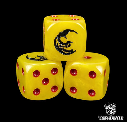 Close up of a yellow 16mm resin D6 die engraved with a black grinning crescent moon and red pips