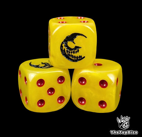 Close up of a yellow 16mm resin D6 die engraved with a black grinning crescent moon and red pips