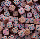 Pile of pink 16mm D6 dice with gold hive sigils for a sci-fi brood army