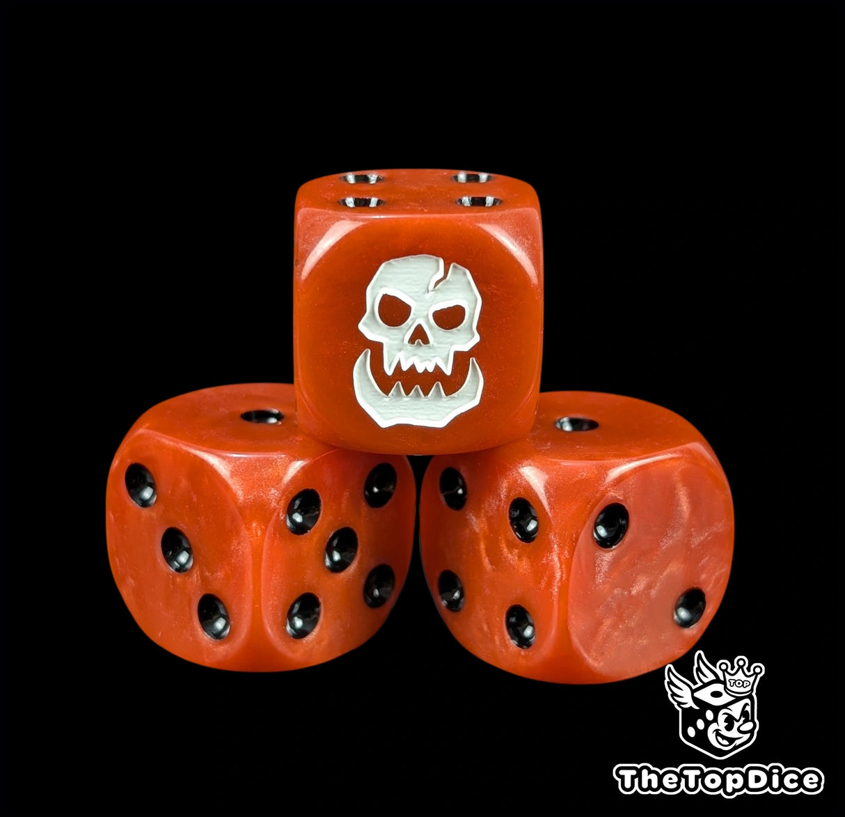 Close up of a red 16mm resin D6 die engraved with a white ork skull and black pips