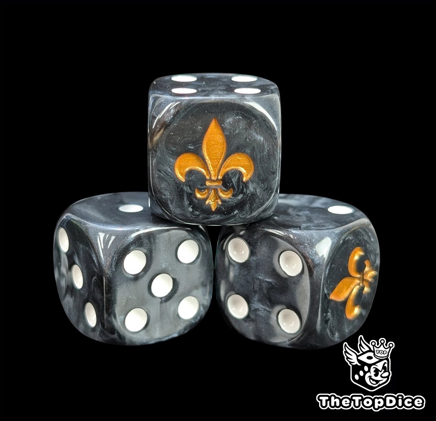 Close-up of a black D6 die with a gold lily emblem