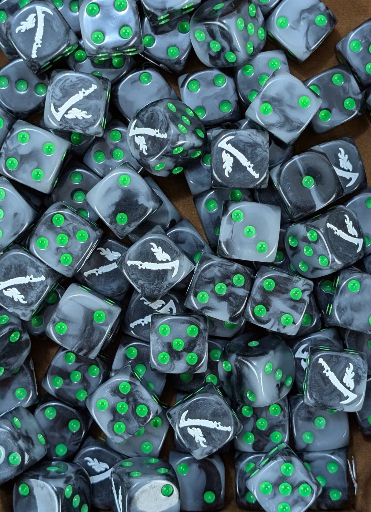 Pile of black and grey 16mm D6 dice with white blade emblems for a sci-fi assassin army
