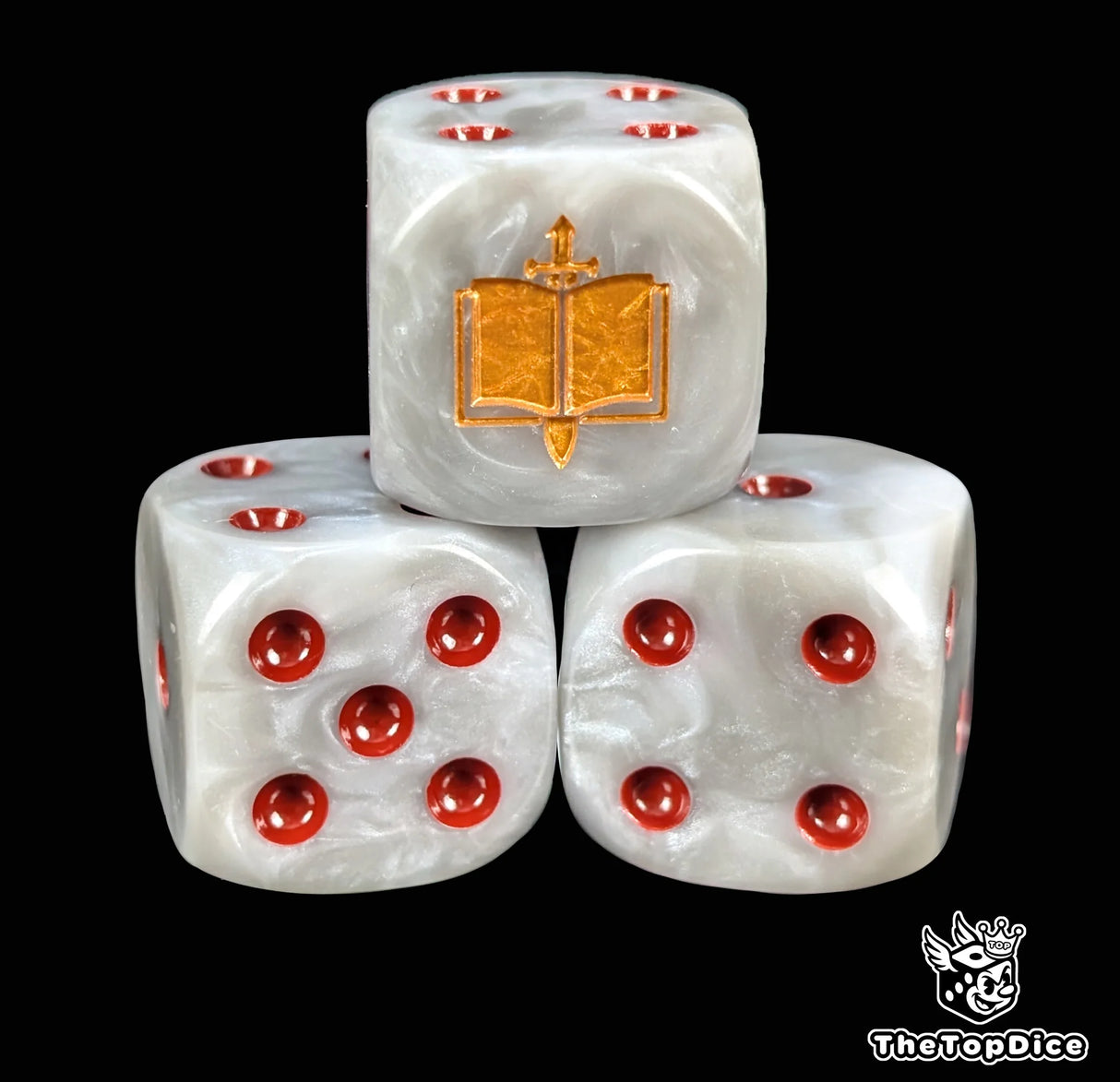 Close up of a grey 16mm resin D6 die engraved with a gold sword piercing a book and red pips