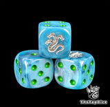 Close up of a teal 16mm resin D6 die engraved with a silver three headed hydra and green pips