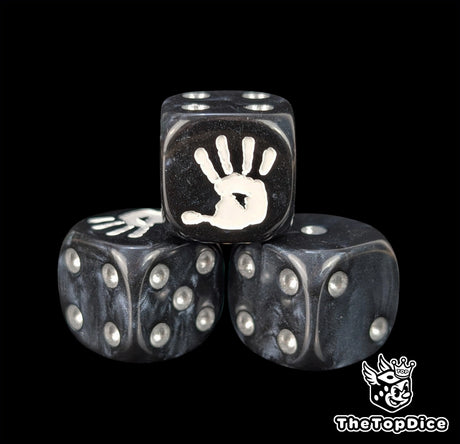 Close up of a black 16mm resin D6 die engraved with a white hand and silver pips
