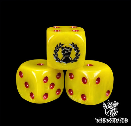 Close up of a yellow 16mm resin D6 die engraved with a black fist and laurel and red pips