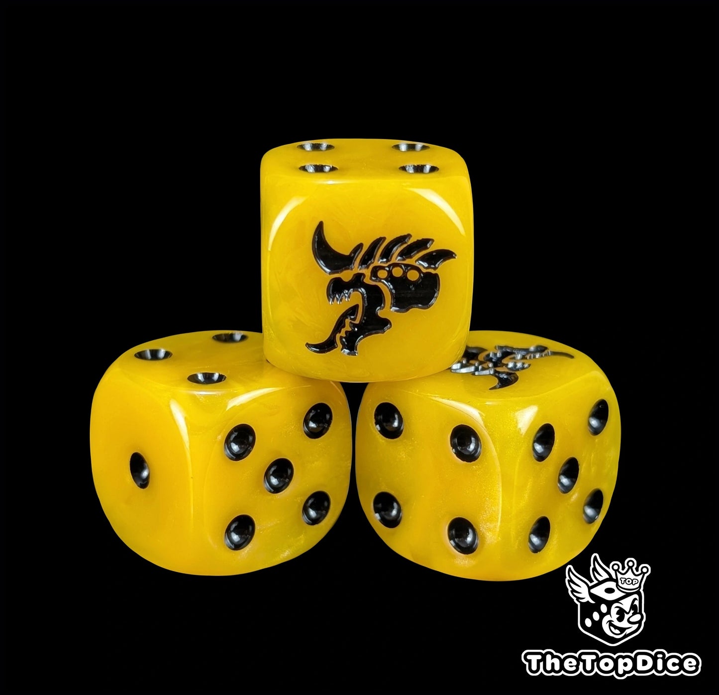 Close up of a yellow 16mm resin D6 die engraved with a black hive alien head and black pips