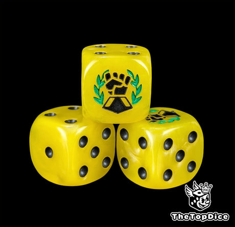 Close up of a yellow 16mm resin D6 die engraved with a black fist and green laurel and black pips